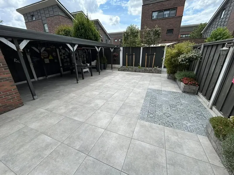 Ruim terras van lichte tegels met een vlak van patroontegels, verhoogde plantenbakken en een overkapping